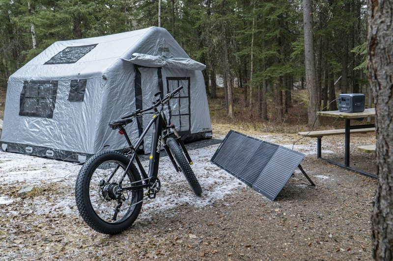 Tente, vélo et panneaux solaires portables dans un camping